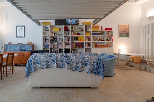 A modern living room with a sofa, a bookshelf, a dining area, and a small table. - Designer Loft in Torino (Turin)