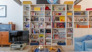 Una sala de estar con una estantería, un televisor y un sofá.