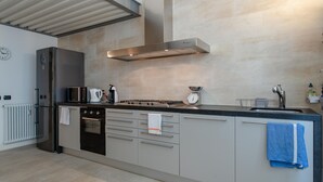 Una cocina moderna con electrodomésticos de acero inoxidable, horno empotrado y una isla grande con lavamanos.