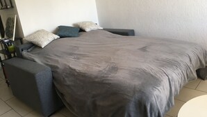 Une chambre à coucher avec un grand lit, une table de chevet, une chaise et une étagère fixée au mur.