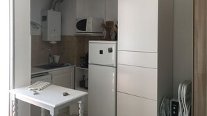 Une cuisine compacte avec un réfrigérateur blanc, un four à micro-ondes et un petit évier.