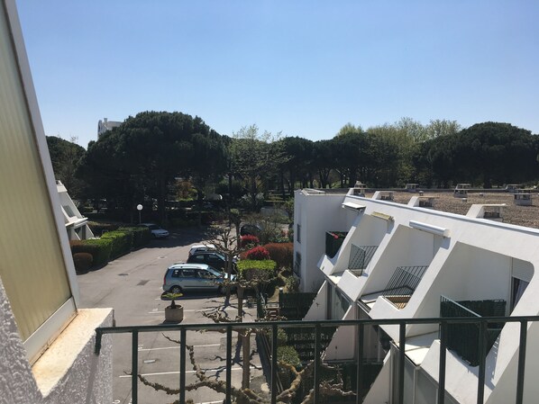 A residential area with white buildings, a parking lot, and trees.