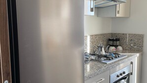 A modern kitchen with a stainless steel Haier refrigerator, a gas stove, and a built-in oven. - Sea House Agadir (Agadir)