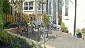 A patio with a table and chairs, a wooden fence, and potted plants. - 2 bedroom accommodation in Warkworth (Warkworth)