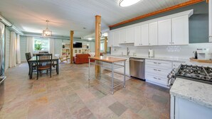 Una cocina amplia con armarios blancos, una isla central y un comedor con mesa y sillas.