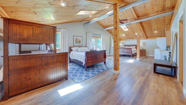 Un dormitorio amplio con una cama grande, un aparador de madera y un tragaluz.
