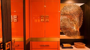 A room with a large red wardrobe, a decorative wall piece, and a bedside table with books and a basket. - House of Hütter - Floating Home Goldfinger (Formentera)