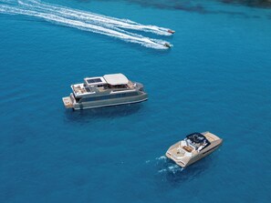 Un grand yacht doté d’un pont couvert et d’un petit bateau à moteur à proximité.