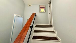 A staircase with wooden steps and a handrail, leading to a door with a window on the landing. - Family-Friendly 3BR/3BA Gainesville Condo Near Downtown & Lake (Gainesville)
