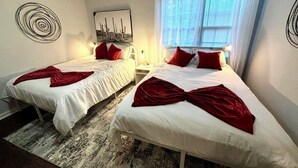A hotel room with two single beds, a large window with blinds, a wall-mounted artwork, and a patterned rug. - Family-Friendly 3BR/3BA Gainesville Condo Near Downtown & Lake (Gainesville)