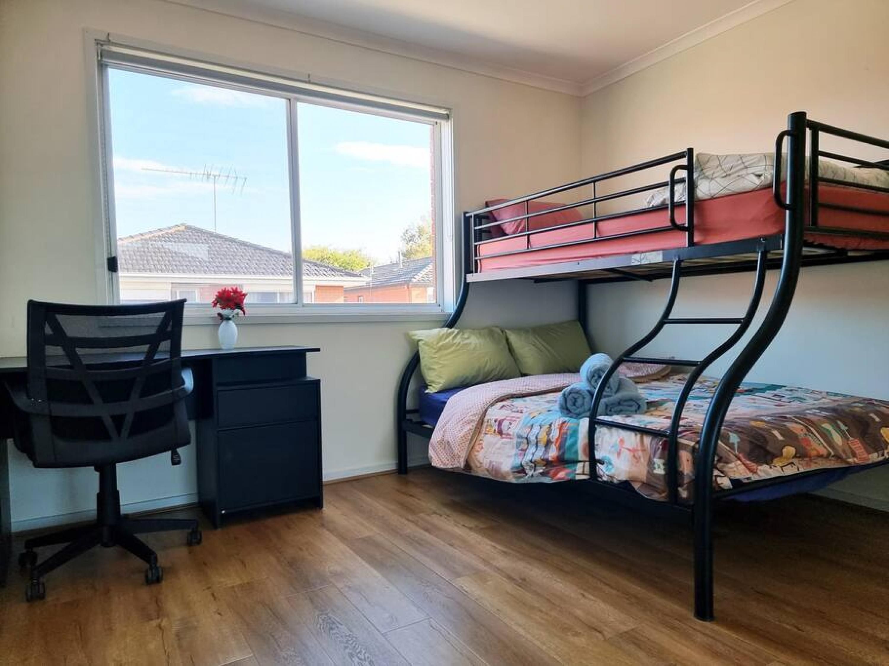 A dorm-style room with a bunk bed, a desk, and a chair.
