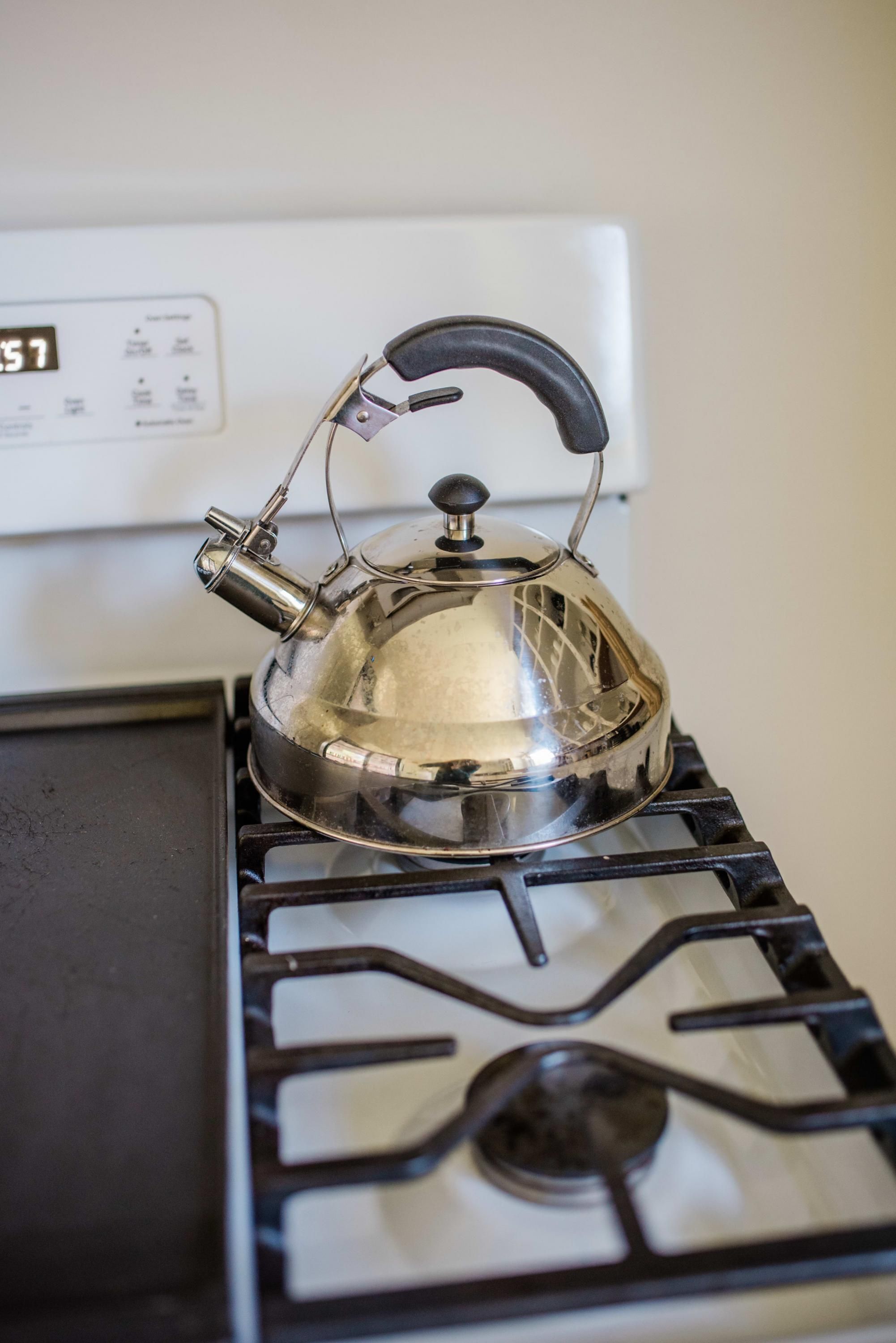 Une bouilloire en acier inoxydable posée sur une cuisinière à gaz.