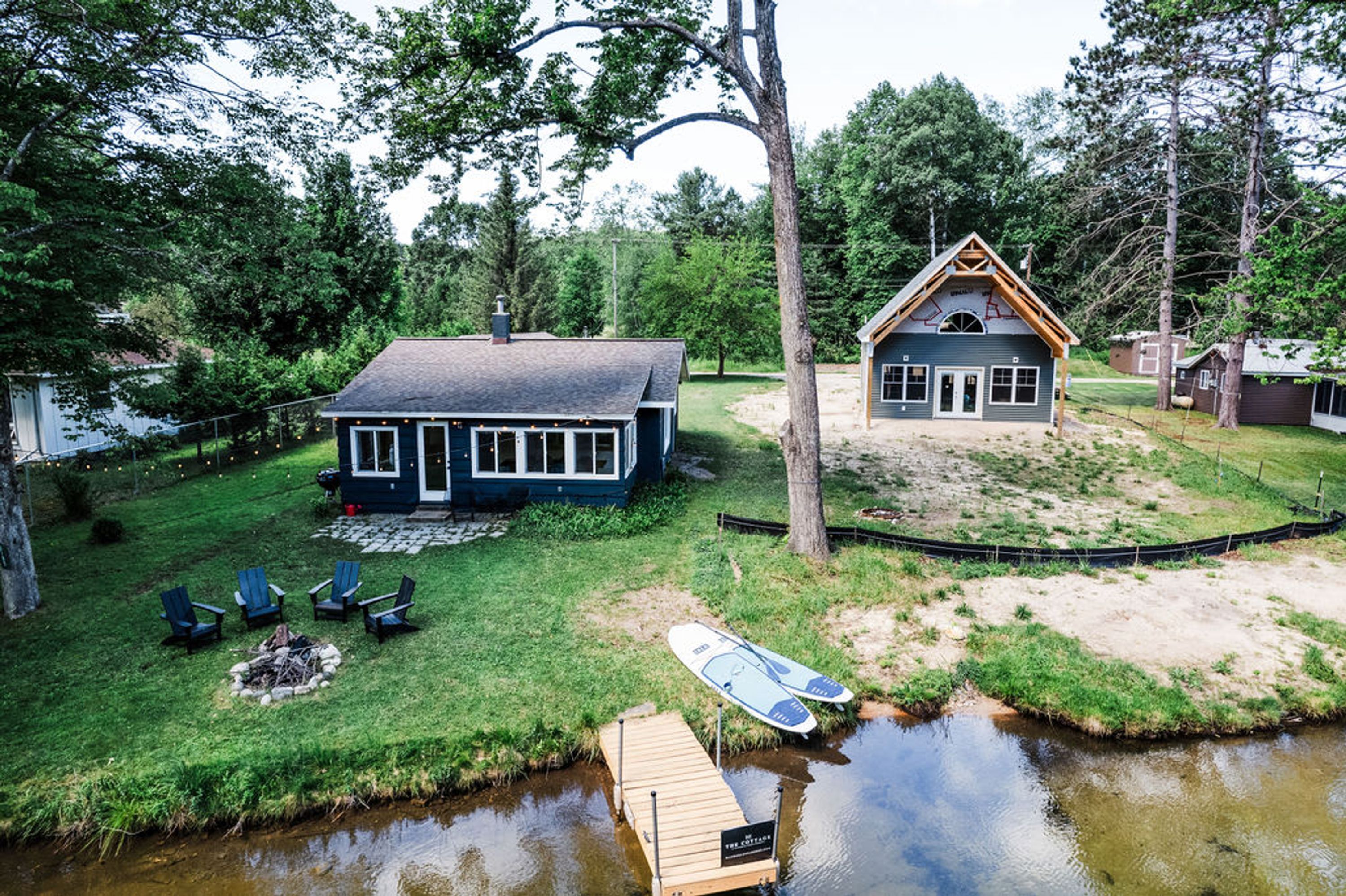 A lakeside cabin with a dock, a fire pit, and outdoor seating.