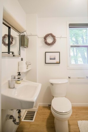 Une salle de bain avec un lavabo blanc, des toilettes et une fenêtre.