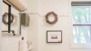 A bathroom with a white sink, toilet, and a window with a view of trees. - Amelia Room BW Boutique Hotel (Central Lake)