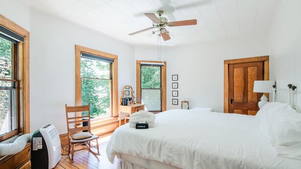 A bedroom with a large bed, a ceiling fan, wooden flooring, and large windows. - Amelia Room BW Boutique Hotel (Central Lake)