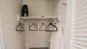 A small, dark wooden cabinet with a single door, a white robe hanging on a rack, and a black device on a shelf above. - Charlie Room BW Boutique Hotel (Central Lake)