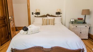 A neatly made bed with a wooden headboard, a bedside table with a lamp, and a stack of books. - Charlie Room BW Boutique Hotel (Central Lake)