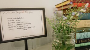 A sign with a list of room amenities and a jar with flowers on a table. - Charlie Room BW Boutique Hotel (Central Lake)