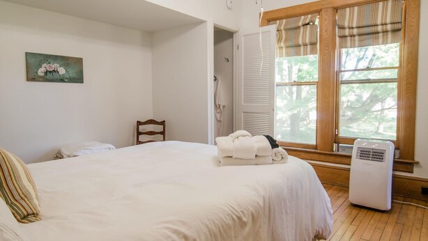 A bedroom with a large bed, a ceiling fan, a window with curtains, and a radiator. - Charlie Room BW Boutique Hotel (Central Lake)
