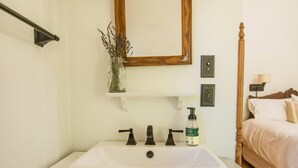 A bathroom with a white sink, wooden cabinet, and a bed with white bedding. - Charlie Room BW Boutique Hotel (Central Lake)
