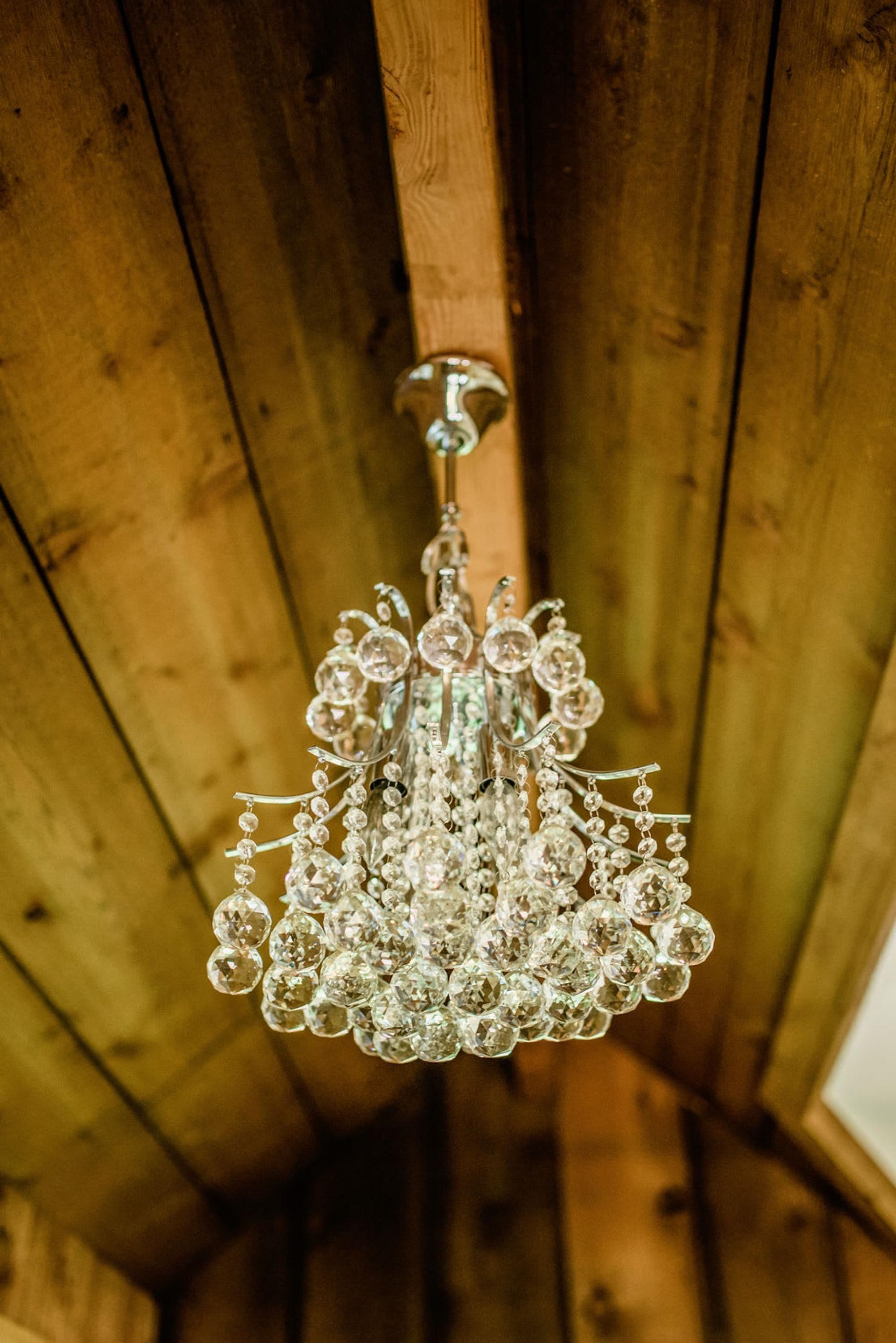Un candelabro con múltiples elementos de cristal colgando de un techo de madera.