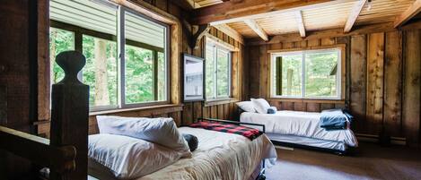 A cabin with two beds, wooden walls, and large windows.