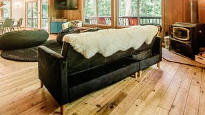 A spacious cabin with a high ceiling, wooden floors, a large sofa, a television, and a fireplace. - Northern Nights Chalet by Wanderlust Abodes (Bellaire)