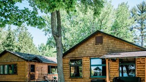 A log cabin with a porch, large windows, and a stone pathway leading to the entrance. - Northern Nights Chalet by Wanderlust Abodes (Bellaire)