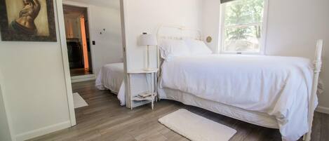 A bedroom with a bed, bedside table, lamp, and a window.