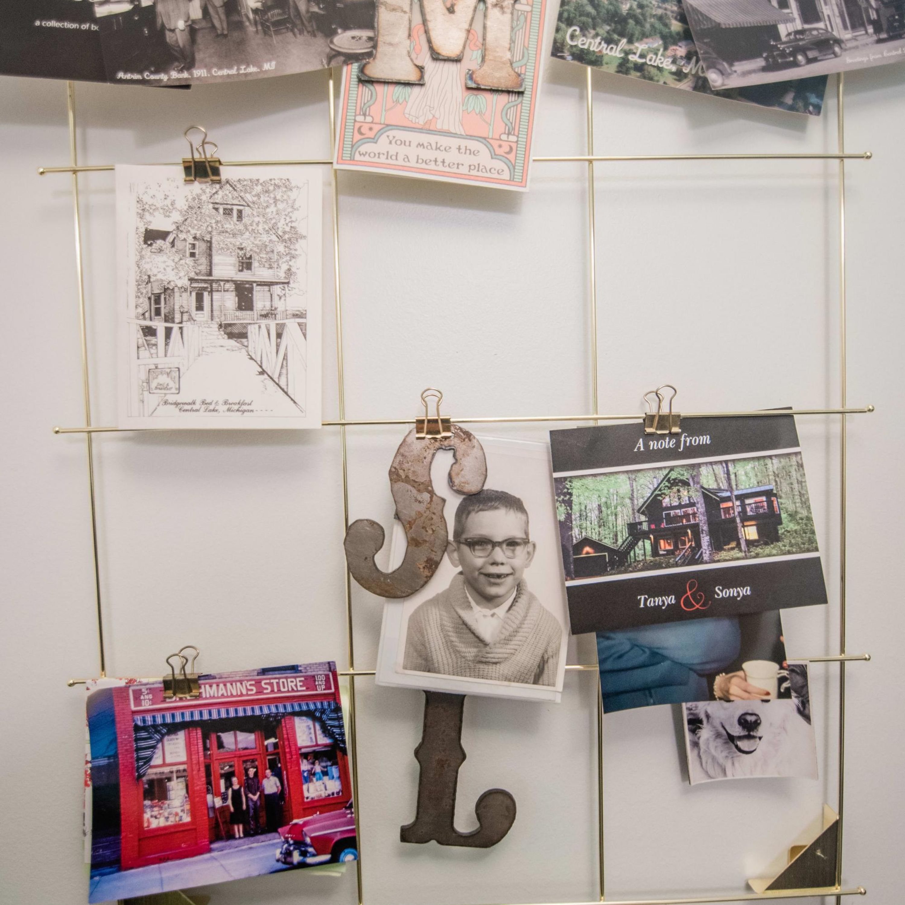 Una pared con varias fotografías y recuerdos, incluyendo un coche antiguo, una casa y la fachada de una tienda.