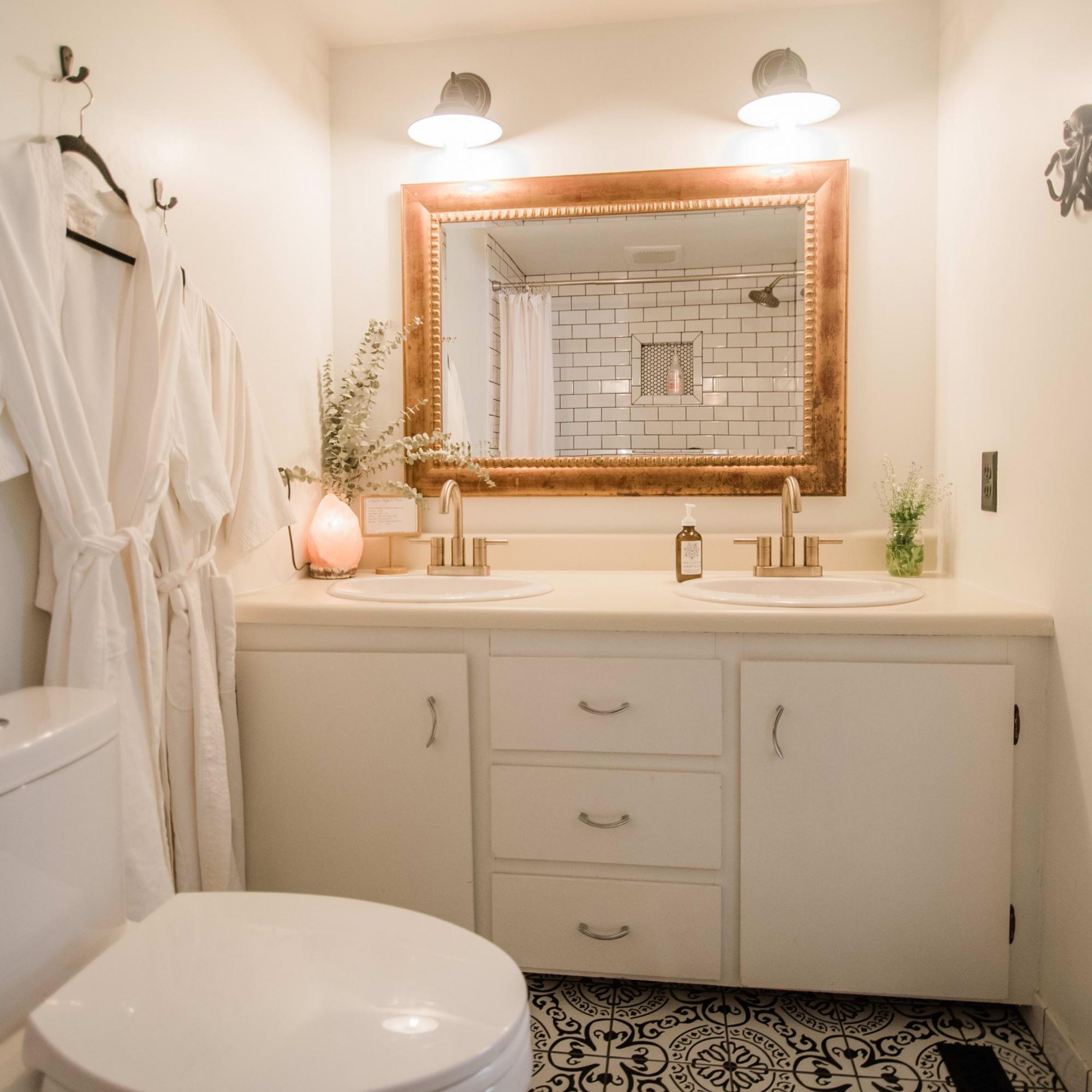 A bathroom with a double sink vanity, a large mirror, and a toilet.