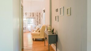 A hallway with a wooden floor, a beige sofa, a small table with a vase, and a wall with framed pictures. - Mahaney Suite BW Boutique Hotel (Central Lake)