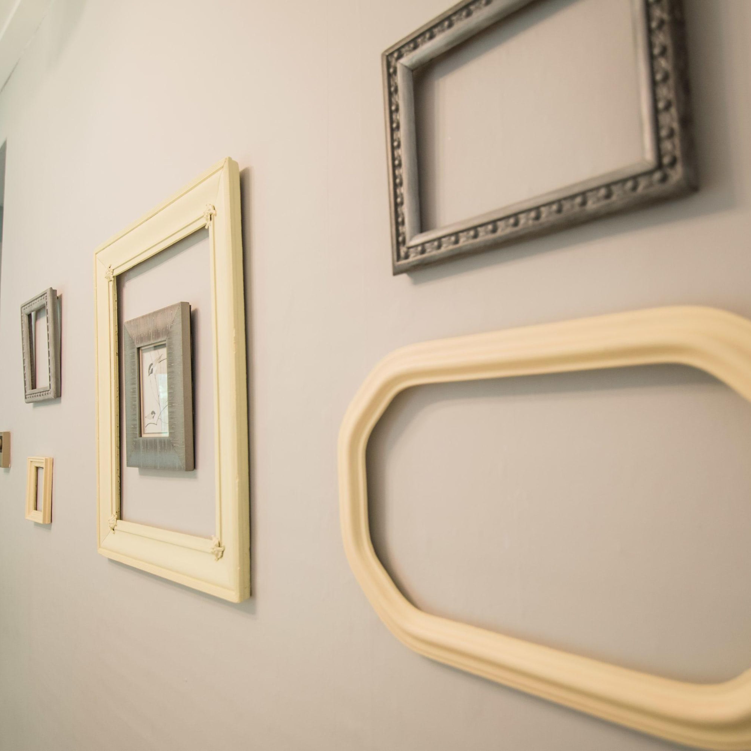 A wall with various picture frames of different sizes and styles.