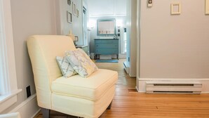 A narrow hallway with a cream-colored armchair and a blue dresser. - Mahaney Suite BW Boutique Hotel (Central Lake)