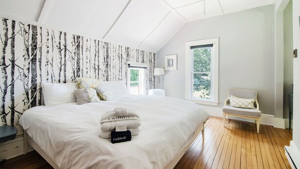 A bedroom with a large bed, a nightstand, a chair, and a window. - Mahaney Suite BW Boutique Hotel (Central Lake)