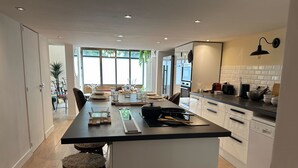 Een moderne keuken met een centraal eiland, witte kasten en uitzicht op de eethoek.