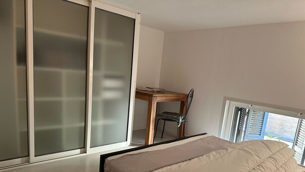 Une chambre à coucher comprenant un lit, une chaise, un bureau et une porte-fenêtre coulissante.