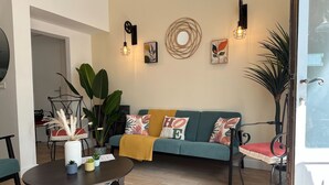 Een moderne woonkamer met een ronde salontafel, een bank met kleurrijke kussens en een grote plant.