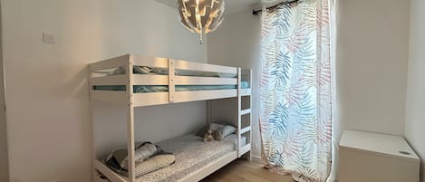 A bunk bed room with a ceiling light fixture and a patterned curtain.