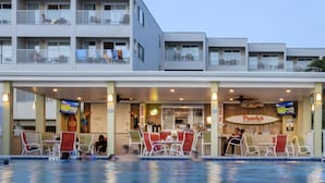 Un hotel con piscina, asientos al aire libre y un restaurante llamado 'Pearly's Beachside'.