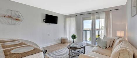 A modern living room with a sofa, coffee table, and a flat-screen TV mounted on the wall.