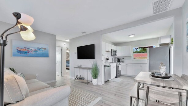 A modern living room with a sofa, a dining table, and a kitchen area in the background. - The Bardmoor a Luxury Family Retreat in St Pete (Seminole)