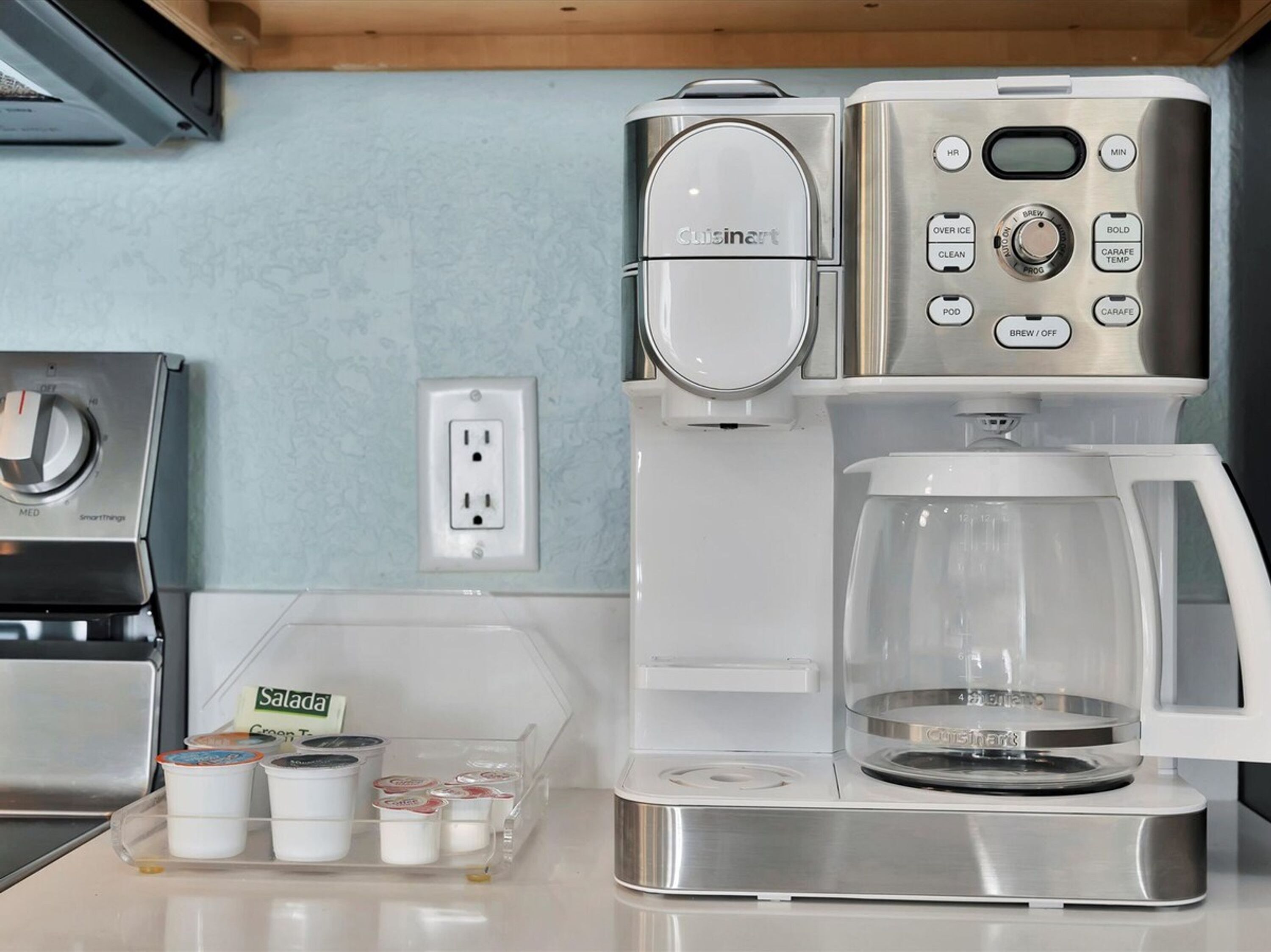 Una kitchenette con cafetera, tostadora y un recipiente con salsas.