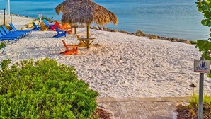 A beach with thatched umbrellas, colorful lounge chairs, and a no-smoking sign. - Oceans Pointe Nantucket Inspired Condo on the bay (Tampa)