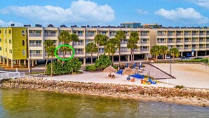A hotel with multiple floors, a beach area with lounge chairs, and a water body in the foreground. - Oceans Pointe Nantucket Inspired Condo on the bay (Tampa)