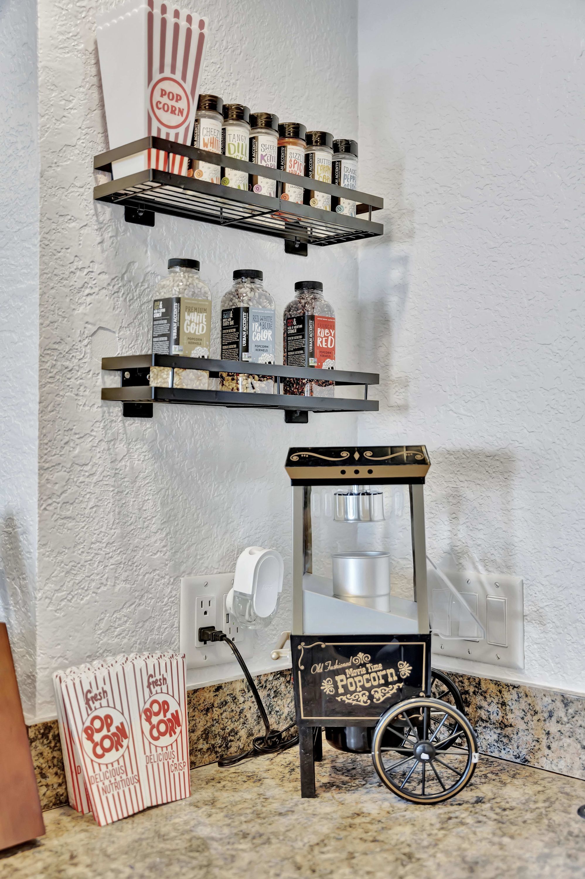 Una cocina con un carrito de palomitas, estantes con condimentos y una caja de palomitas.