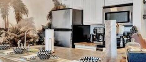 A modern kitchen with white cabinetry, stainless steel appliances, and a marble countertop.