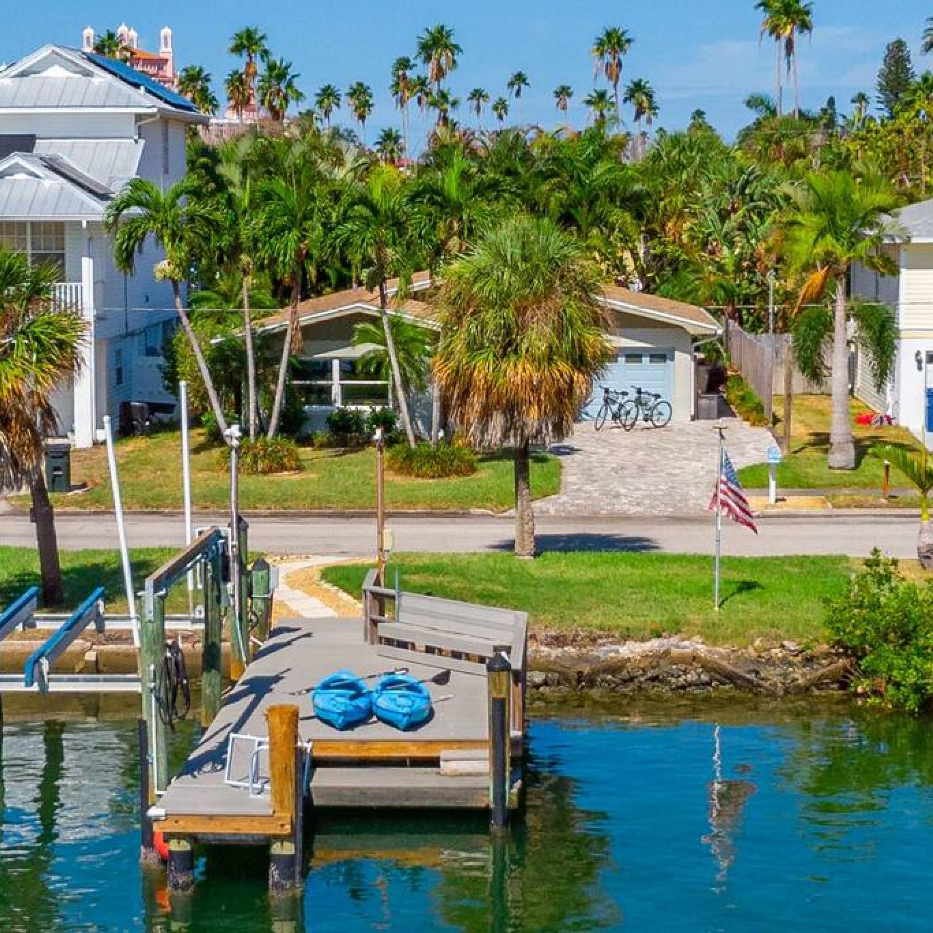 A dock with a boat, surrounded by palm trees and houses.