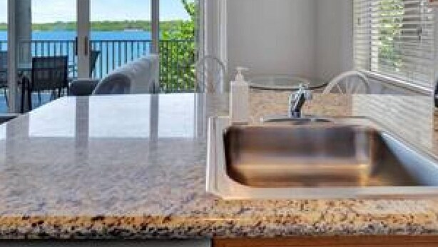 A kitchen with a large window, a sink, and a view of the outdoors. - The Bayview a Quaint 1 1 Balcony on the bay (St. Petersburg)